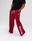 Male model wearing RUDIS Hex Flannel Lounge Pants in Red plaid, featuring an adjustable white drawstring waist, side pockets and WRESTLING graphic. Copy Alt Text