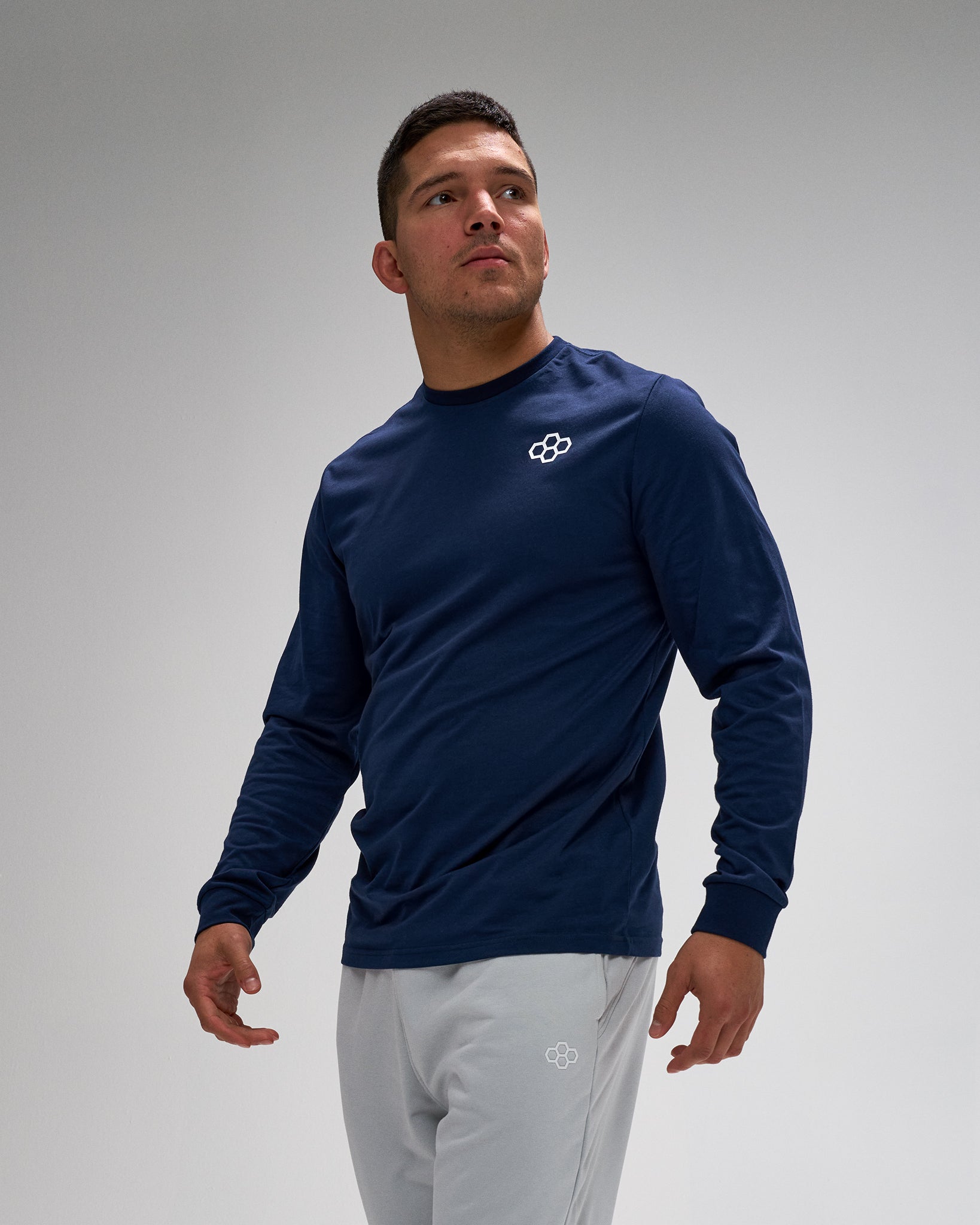 Man wearing a navy long-sleeve shirt with a logo on a gray background