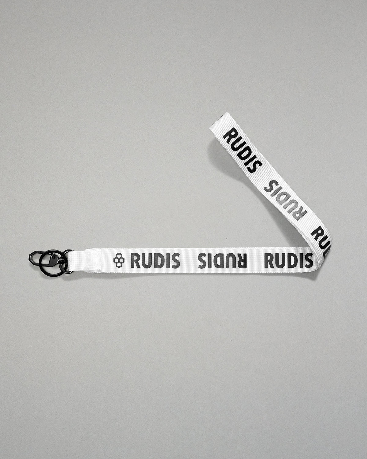white RUDIS Wordmark lanyard with repeating white RUDIS logos, woven polyester strap, metal key clip, and key ring for carrying keys, badges, or accessories.