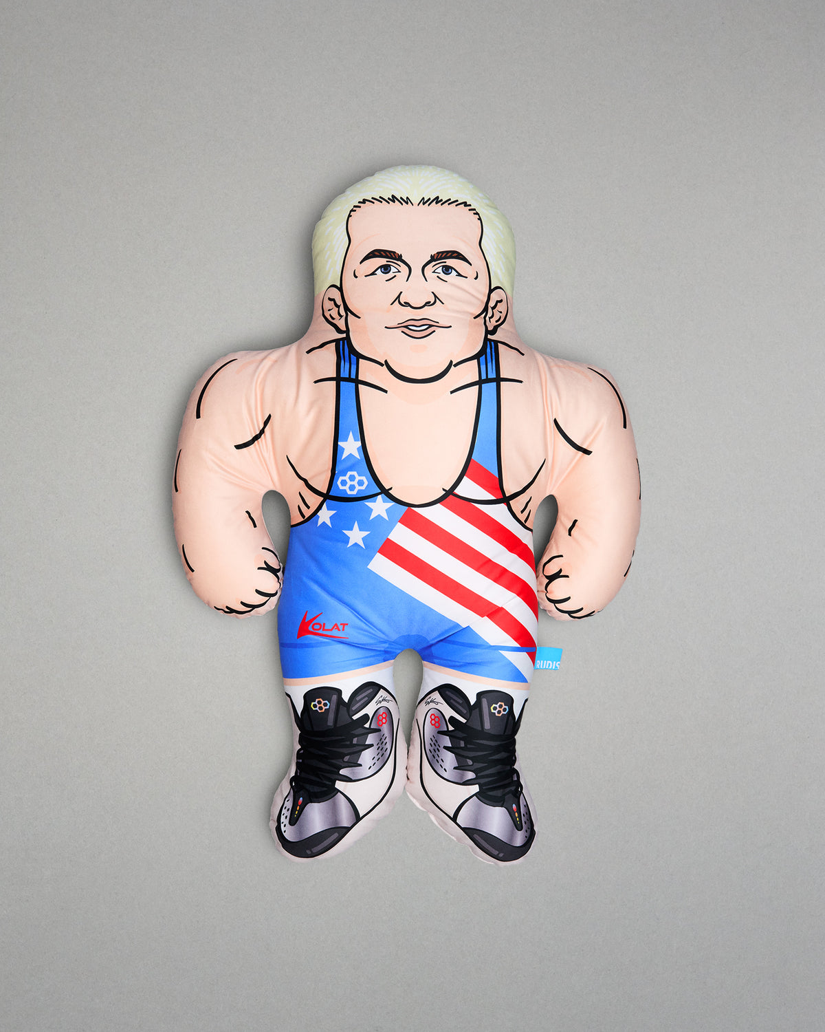 Pillow of a muscular character wearing an American flag wrestling singlet on a gray background