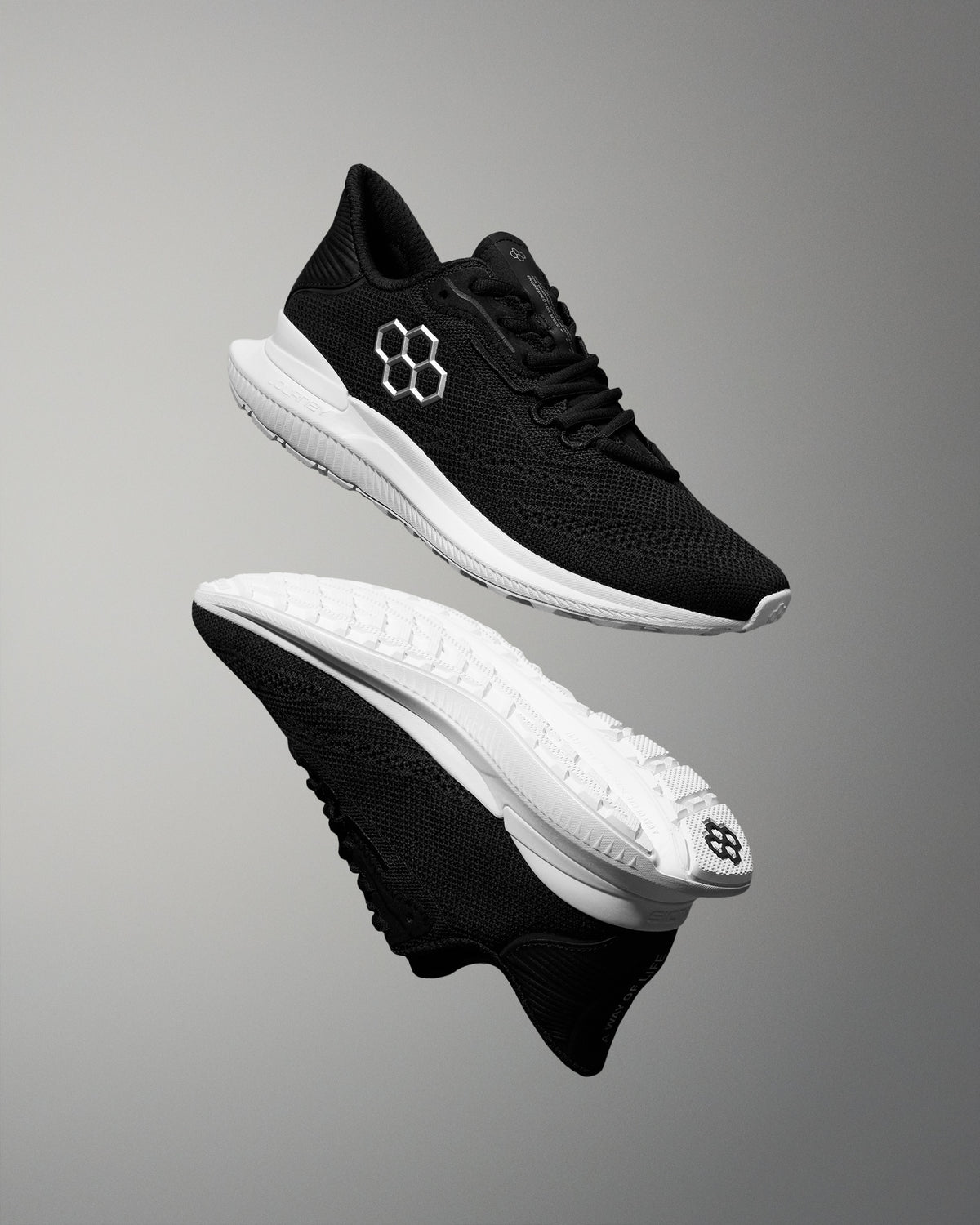 Black running shoes with white soles on a gray background