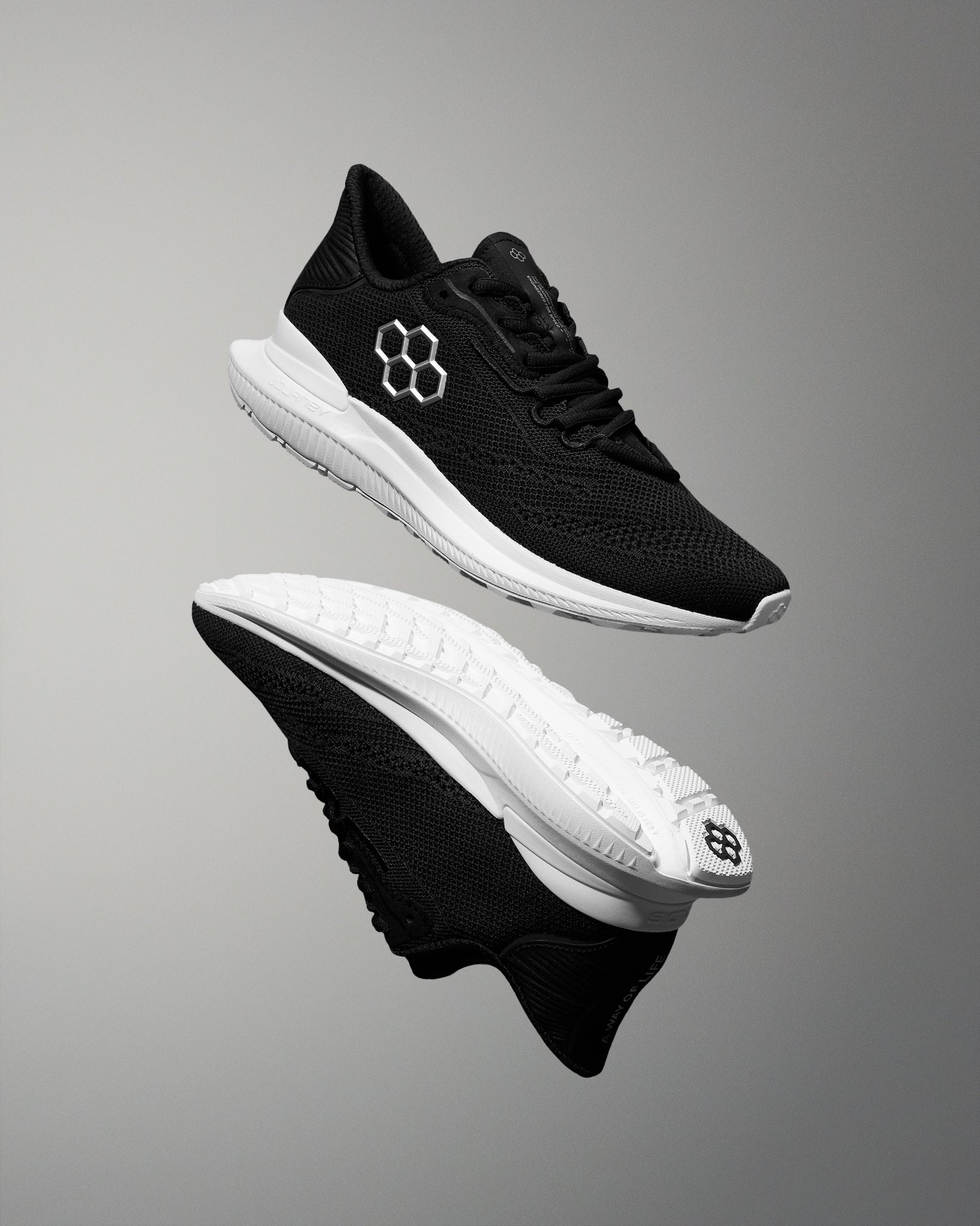 Black running shoes with white soles on a gray background