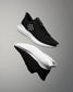 Black running shoes with white soles on a gray background