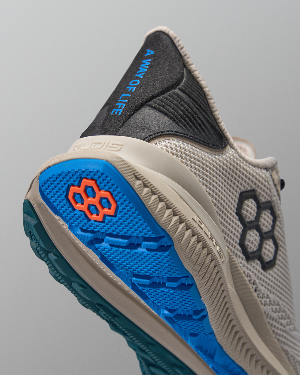Beige training shoe with blue sole and black accents on a gray background