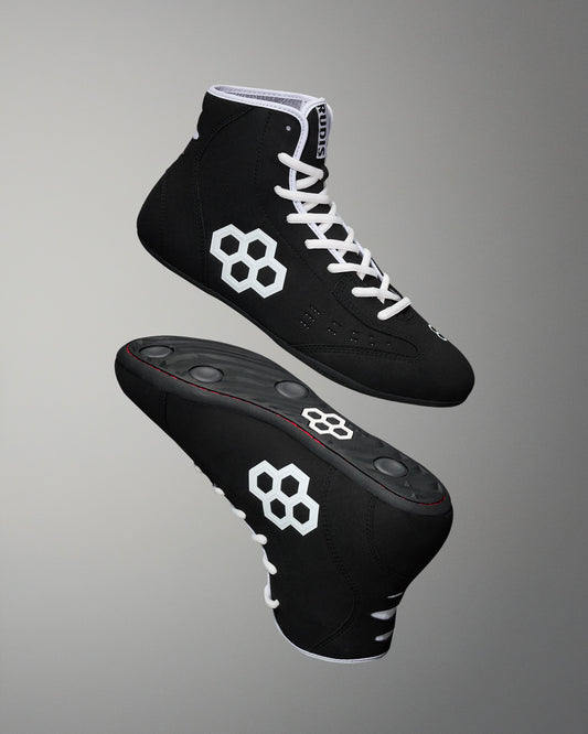Hero image of the RUDIS international wrestling shoe - black/white on a grey background. 