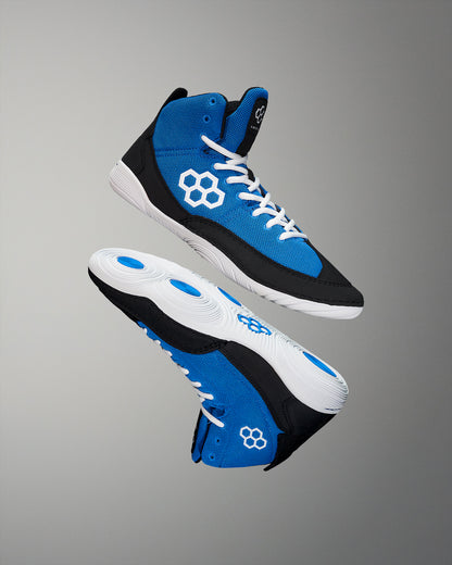 Blue Wrestling shoes feature a vibrant blue upper and black paneling, with white accents and a focus on traction, set against a neutral gray backdrop.