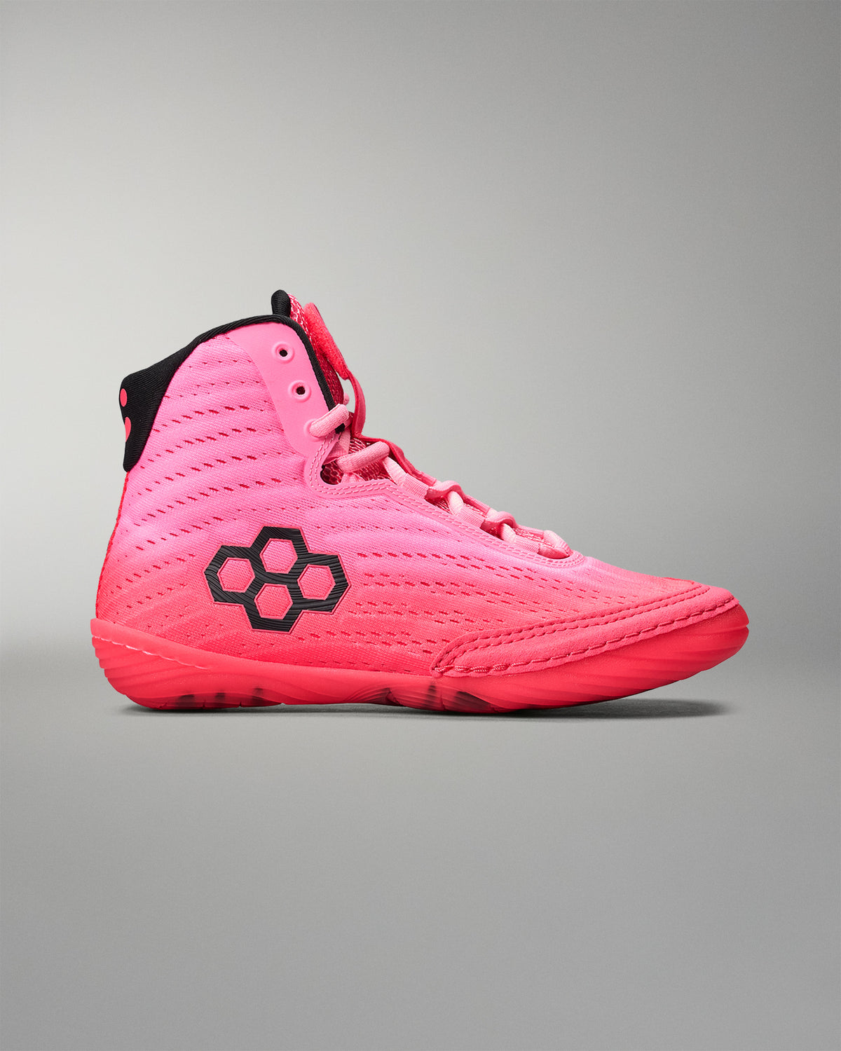Pink wrestling shoe with black sole on a gray background