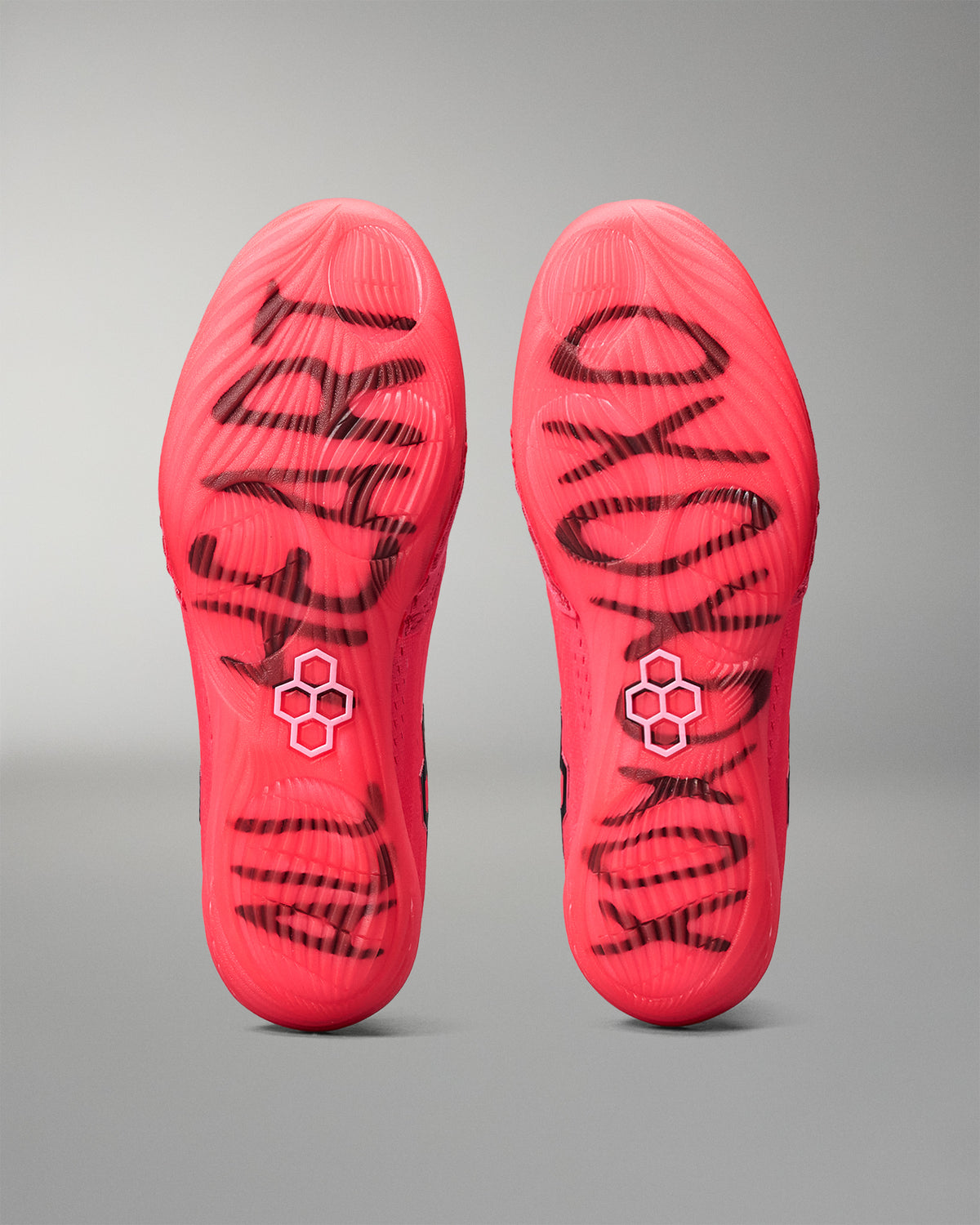 Red wrestling shoe insoles with black branding on a gray background