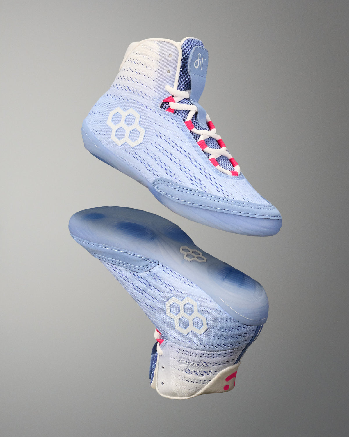 Light blue wrestling shoes with white and pink accents on a gray background