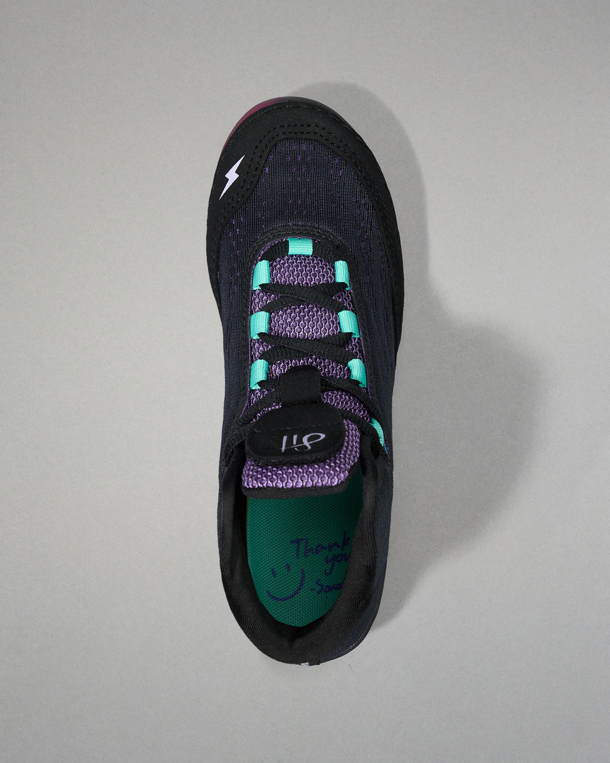 Black athletic shoe with purple accents on a gray background
