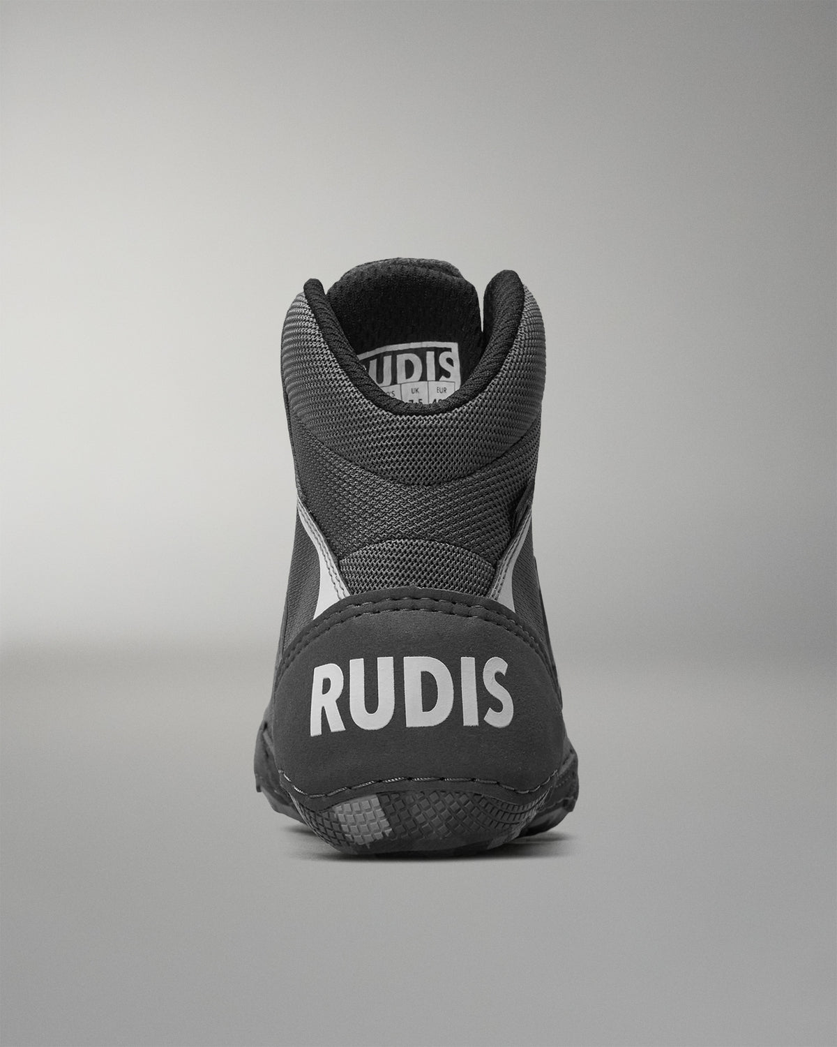 Black wrestling shoe with 'RUDIS' branding on a gray background