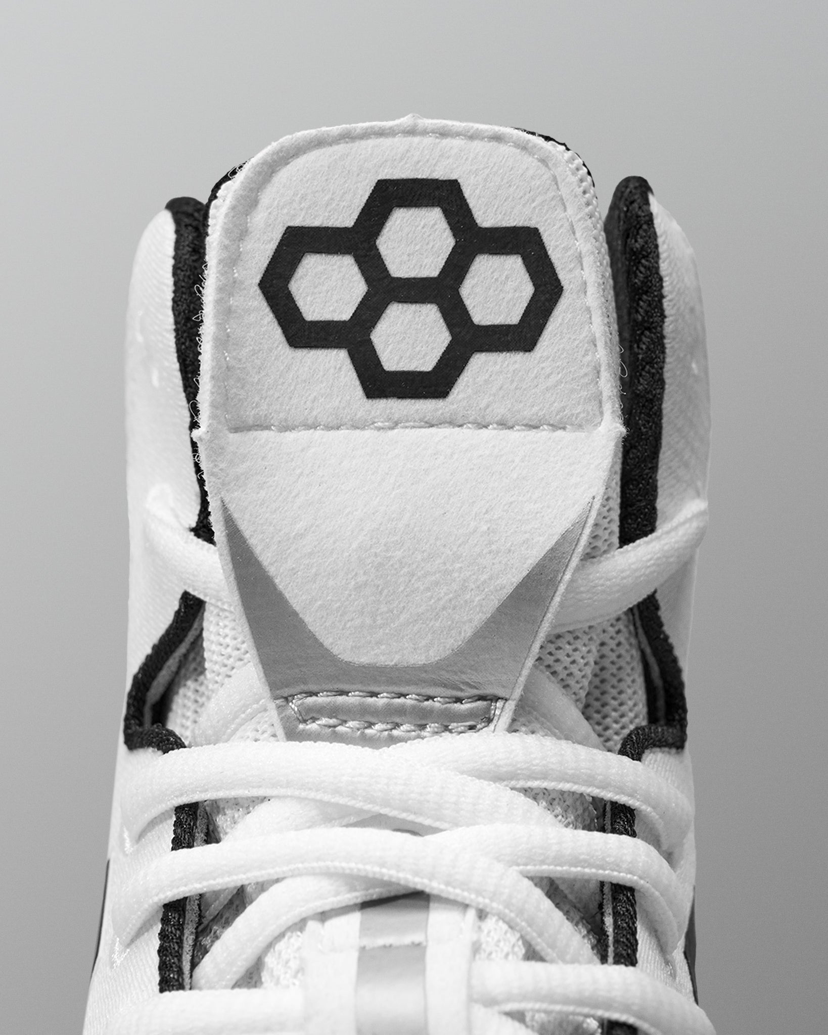 White Wrestling shoe with black hexagonal logo on a gray background
