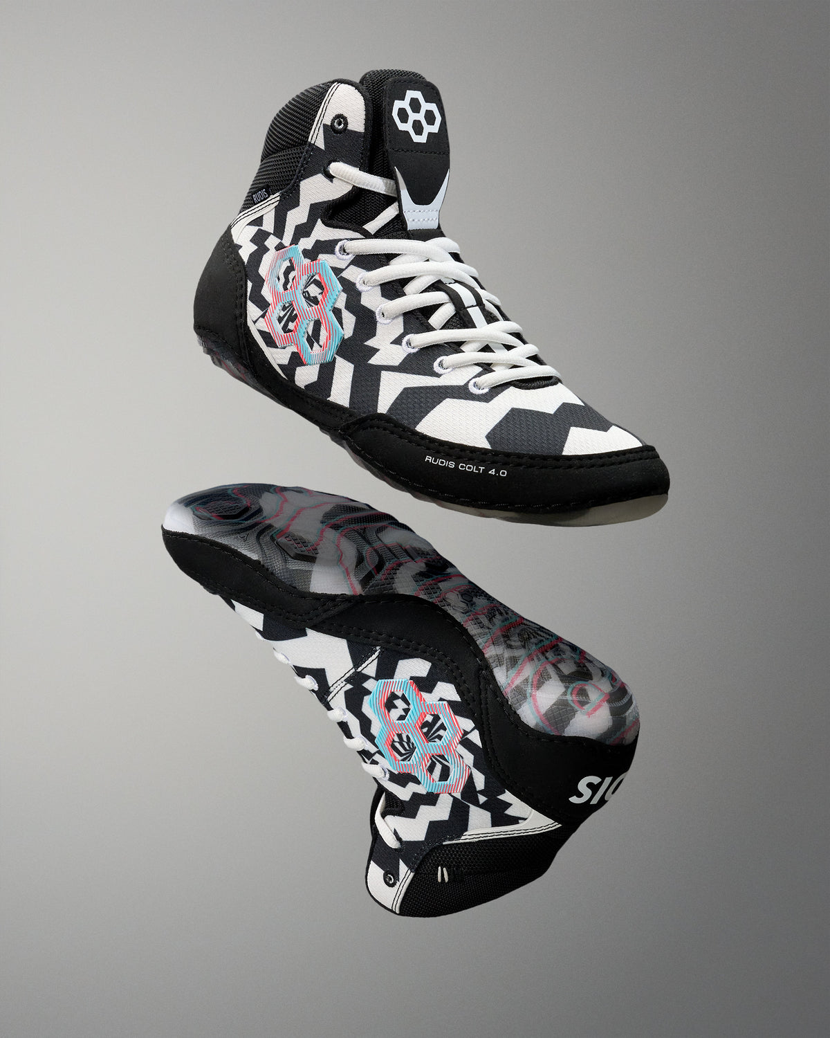 A pair of high-top athletic wrestling shoes shown from the front and side against a neutral gray gradient background. The shoes feature a black, white, and gray geometric pattern with pink and light blue graphic accents on the sides and a white flower logo on the tongue.