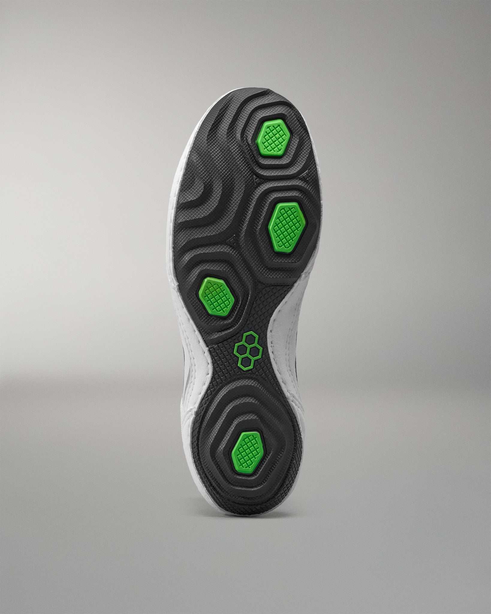 Close-up of a wrestling shoes sole with green hexagonal patterns on a gray background