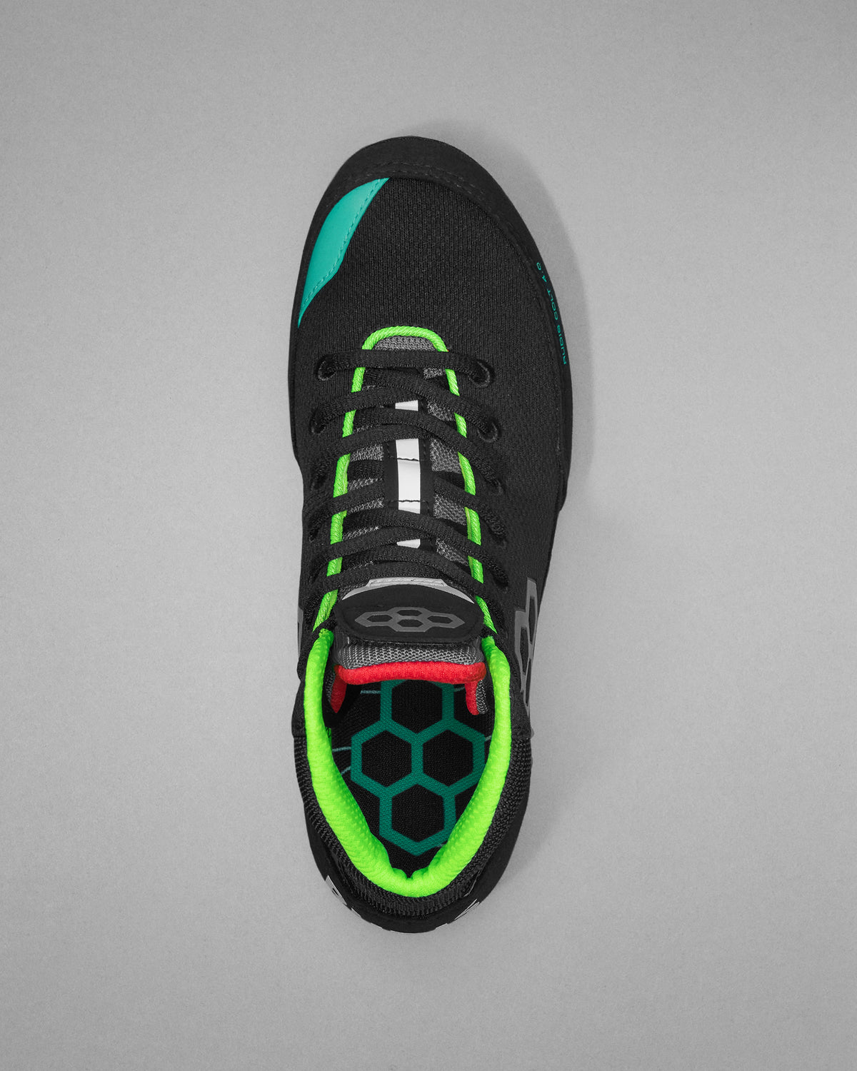 Black wrestling shoe with green and red accents on a gray background