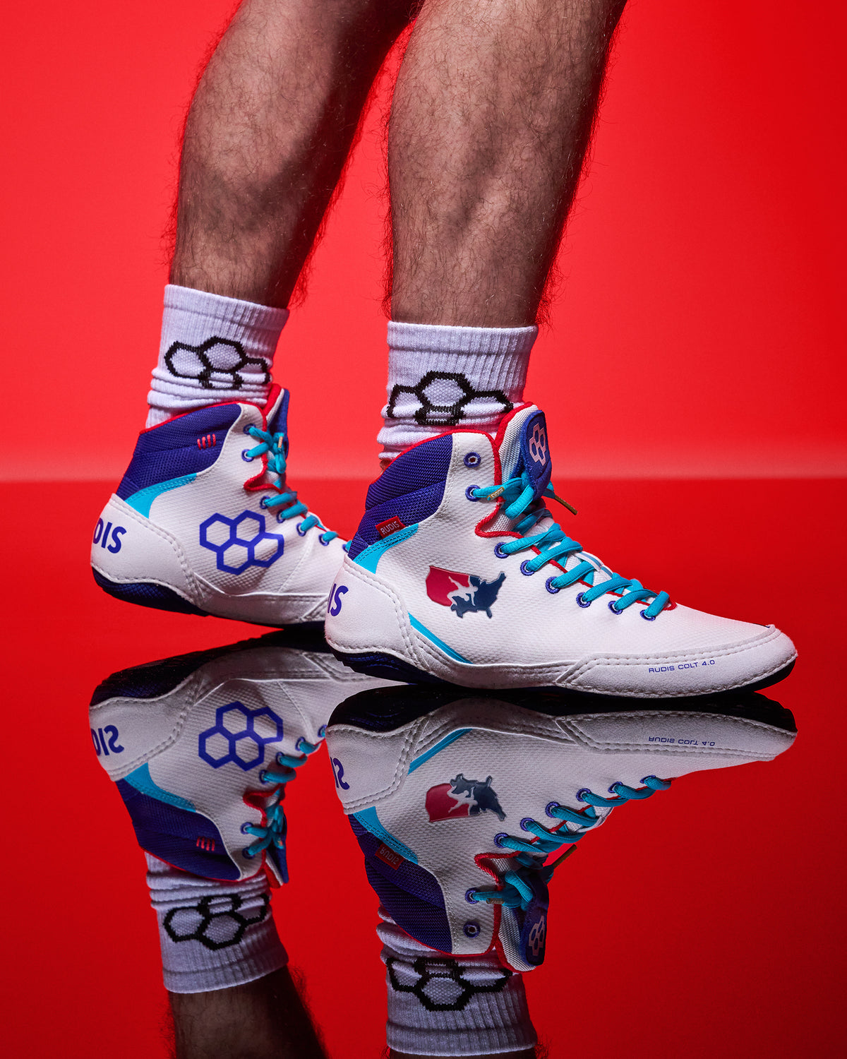 White USA Wrestling Shoes with blue and red accents on a red background