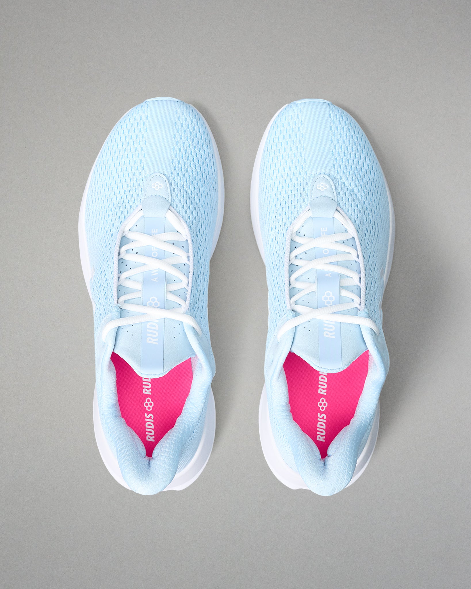 Light blue running shoes with pink insoles on a gray background