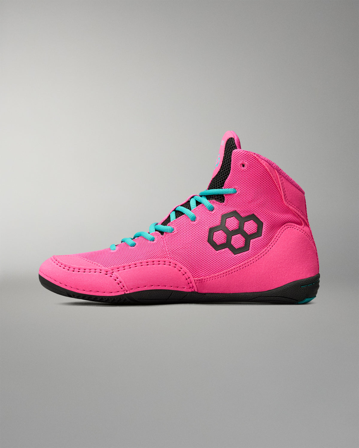 A high-top wrestling shoe in bright pink with turquoise laces, a black hexagonal logo on the side, and a black sole, shown against a neutral gray background.