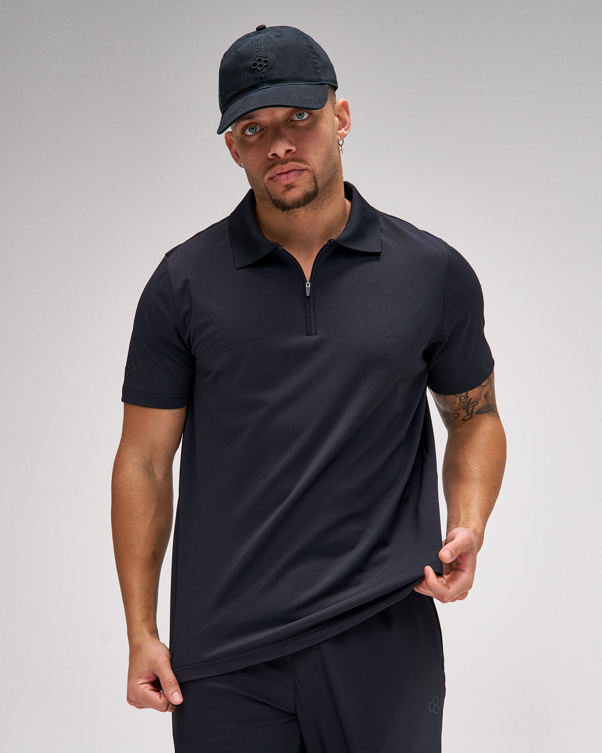 Man wearing a black polo shirt and cap on a gray background