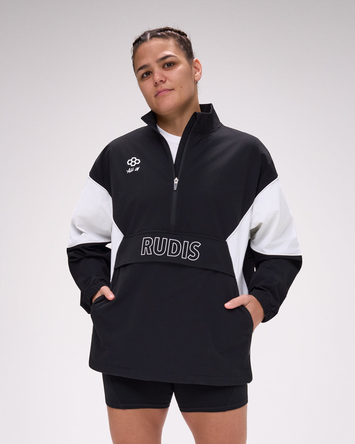 Person wearing a black and white pullover with 'RUDIS' branding on a plain background