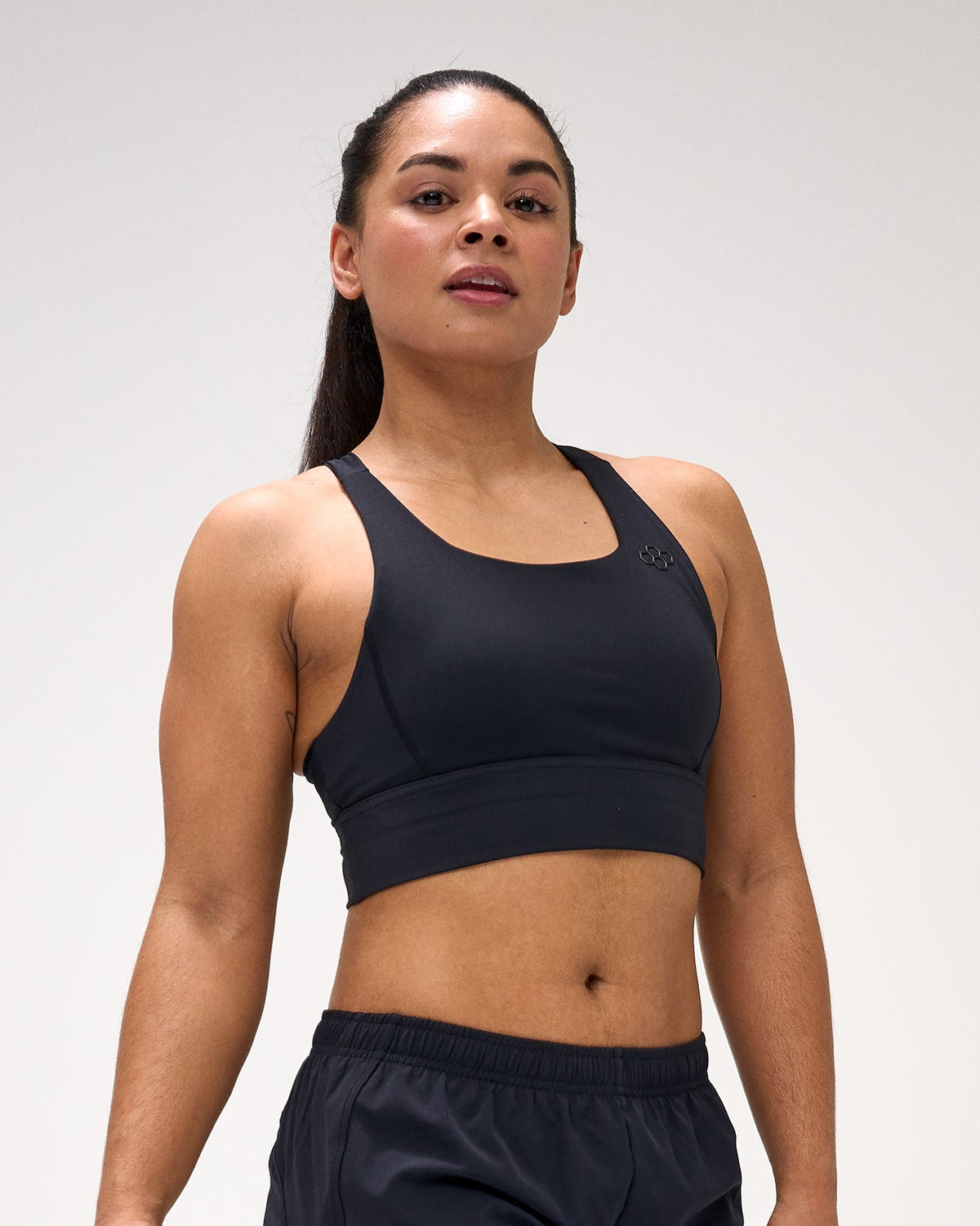 Woman wearing a black sports bra and shorts with a logo on a white background
