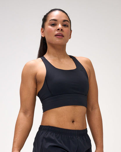 Woman wearing a black sports bra and shorts with a logo on a white background