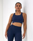 Woman wearing a navy blue sports bra and leggings against a white background