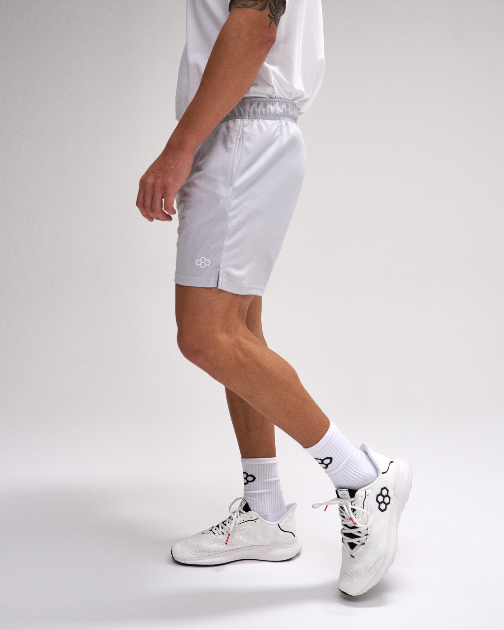 Person wearing white athletic shorts and shoes on a plain background