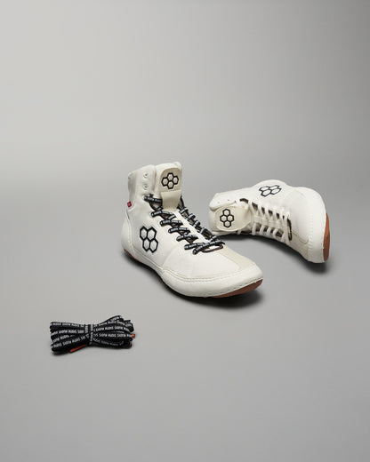 A pair of modern white high-top shoes with black accents and a pair of patterned black laces presented against a neutral background
