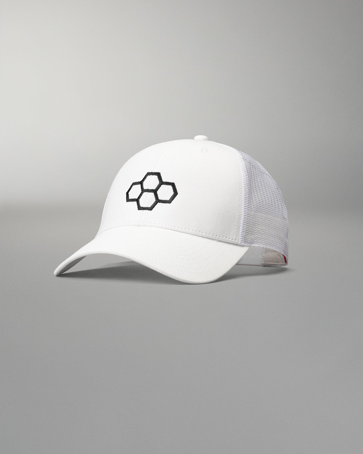 Front angled view of the RUDIS Bridge Trucker Hat in White, featuring an embroidered black RUDIS Bridge logo, curved brim and breathable white mesh panels.