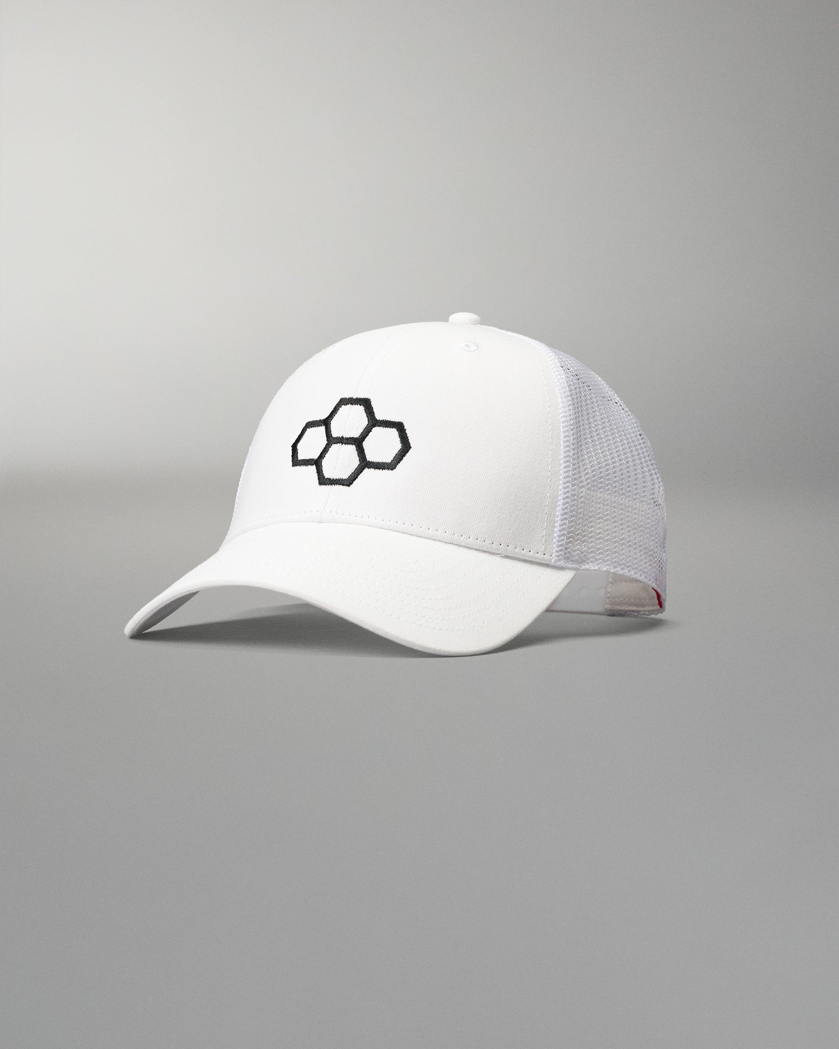 Front angled view of the RUDIS Bridge Trucker Hat in White, featuring an embroidered black RUDIS Bridge logo, curved brim and breathable white mesh panels.