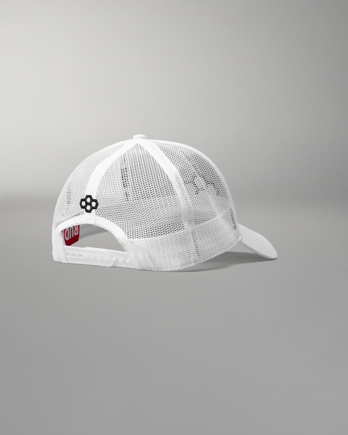 Rear angled view of the RUDIS Bridge Trucker Hat in White, showcasing breathable white mesh panels, an adjustable snapback closure and embroidered black RUDIS emblem.