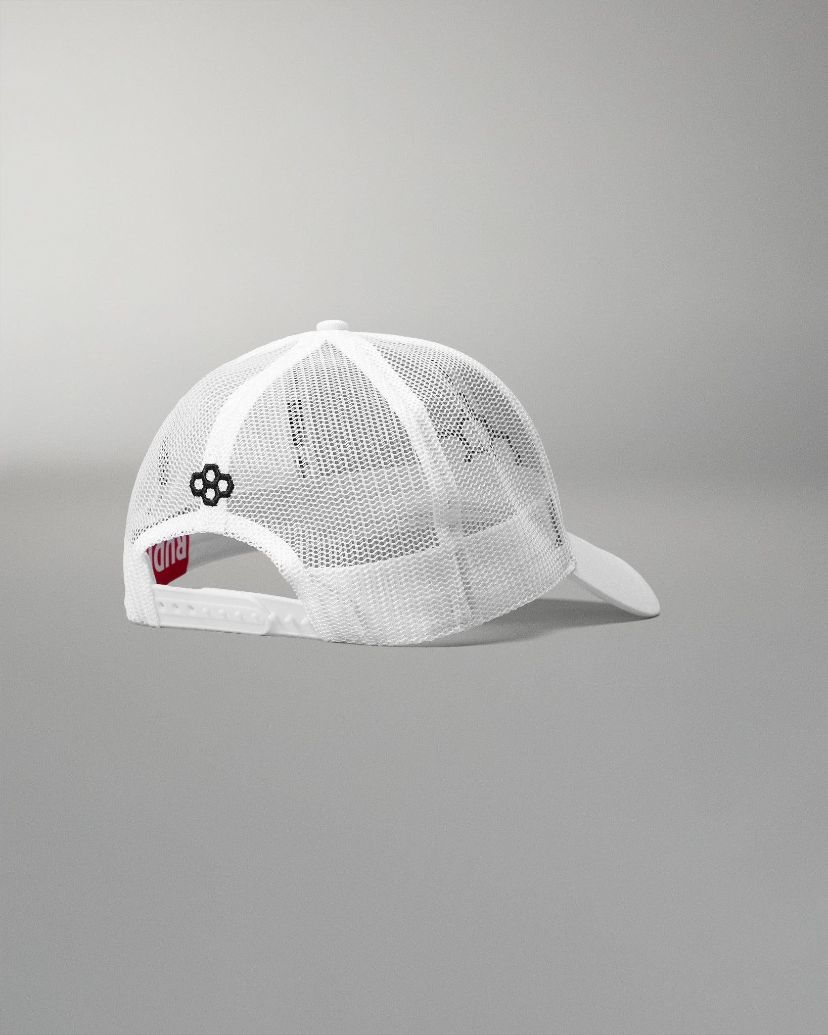 Rear angled view of the RUDIS Bridge Trucker Hat in White, showcasing breathable white mesh panels, an adjustable snapback closure and embroidered black RUDIS emblem.