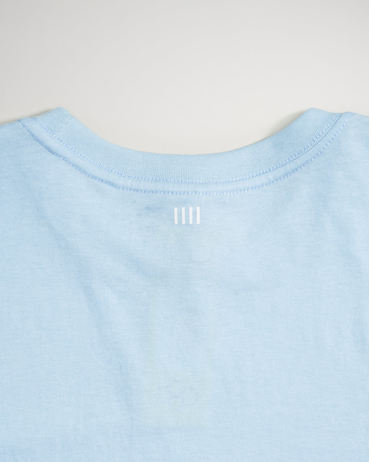 A light blue T-shirt featuring a simple modern design with a subtle white graphic at the neckline