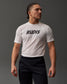 A confidently posed young man with braided hair wears a white 'RUDIS' t-shirt and black sweatpants, highlighted against a soft gray background.
