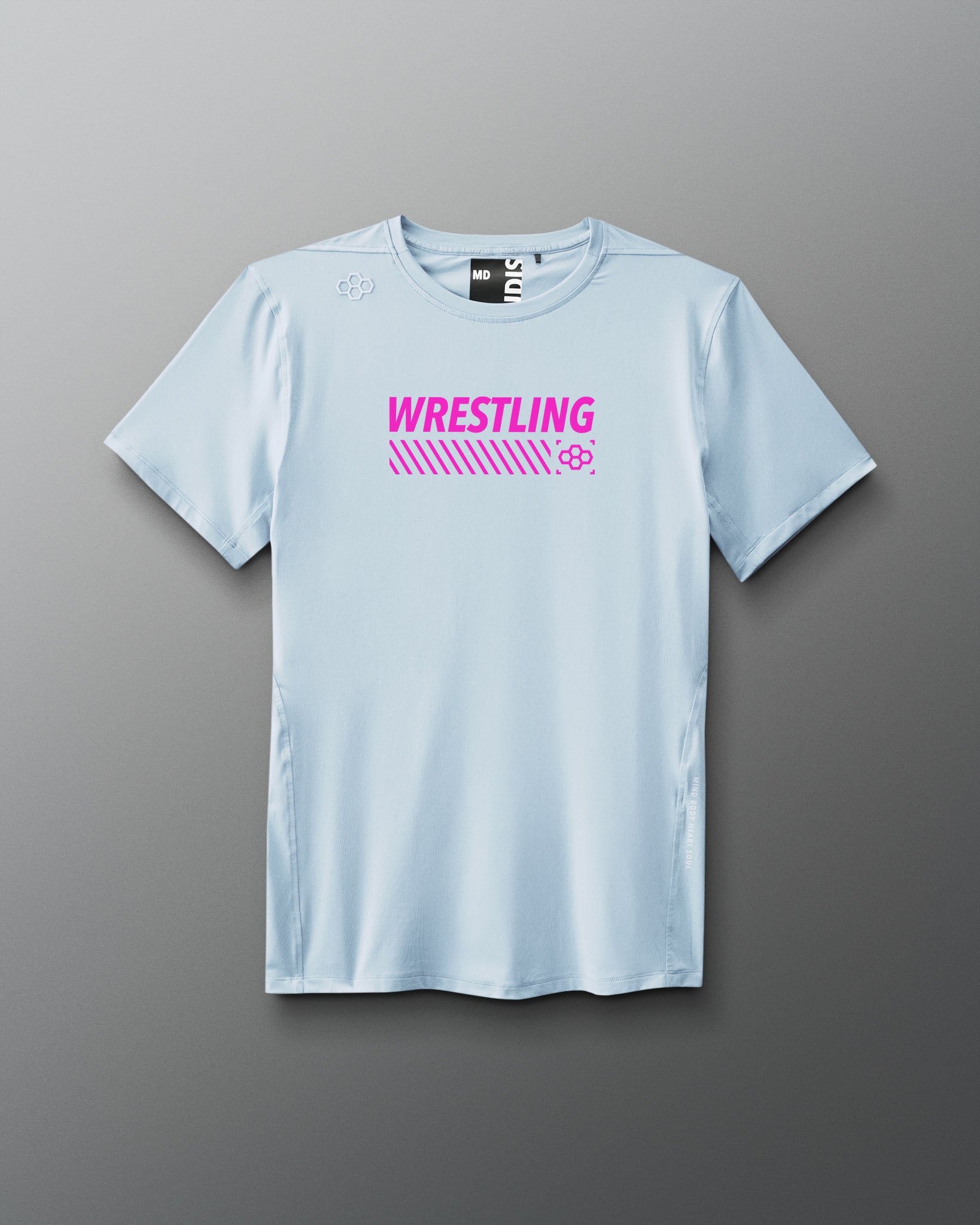 A light blue short-sleeve athletic T-shirt is displayed against a neutral gray background. Bold pink text reading “WRESTLING” is centered on the chest above angled stripes and a small pink RUDIS hex logo. The shirt has an athletic cut with minimal seams and a modern fit.