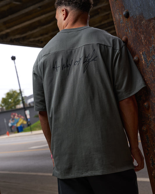 Person wearing a green shirt with text on the back, standing outdoors.