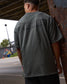 Person wearing a green shirt with text on the back, standing outdoors.