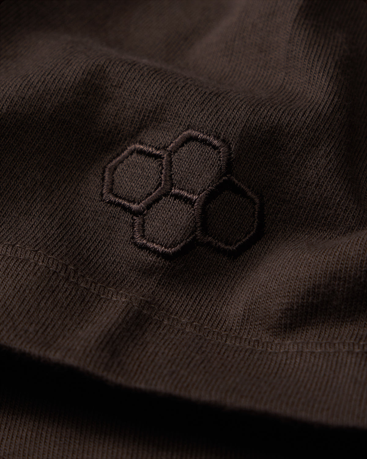 Close-up of a black embroidered design on a dark fabric surface