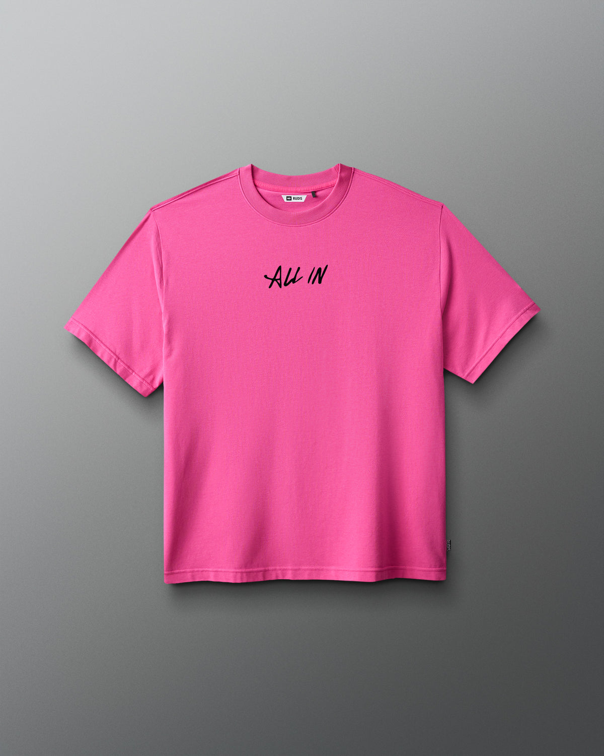 A bright pink short-sleeve crewneck t-shirt with the words 'ALL IN' printed in black script across the chest, displayed against a dark gray gradient background.