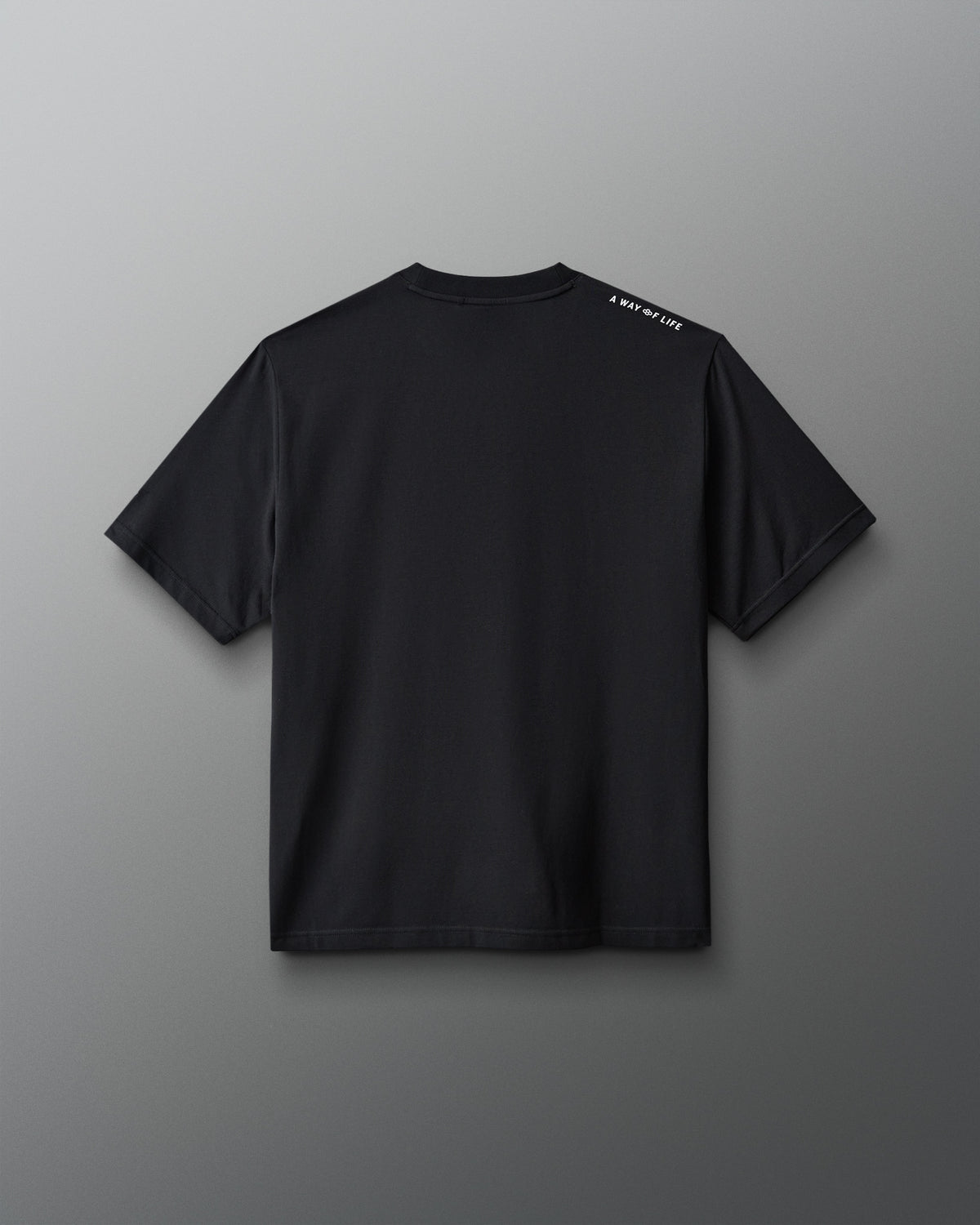 A black short-sleeve t-shirt shown from the back, featuring a small white text print on the left shoulder, displayed against a neutral gray background.