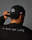 Person wearing a black cap with a logo and a black jacket with 'A Way of Life' text.