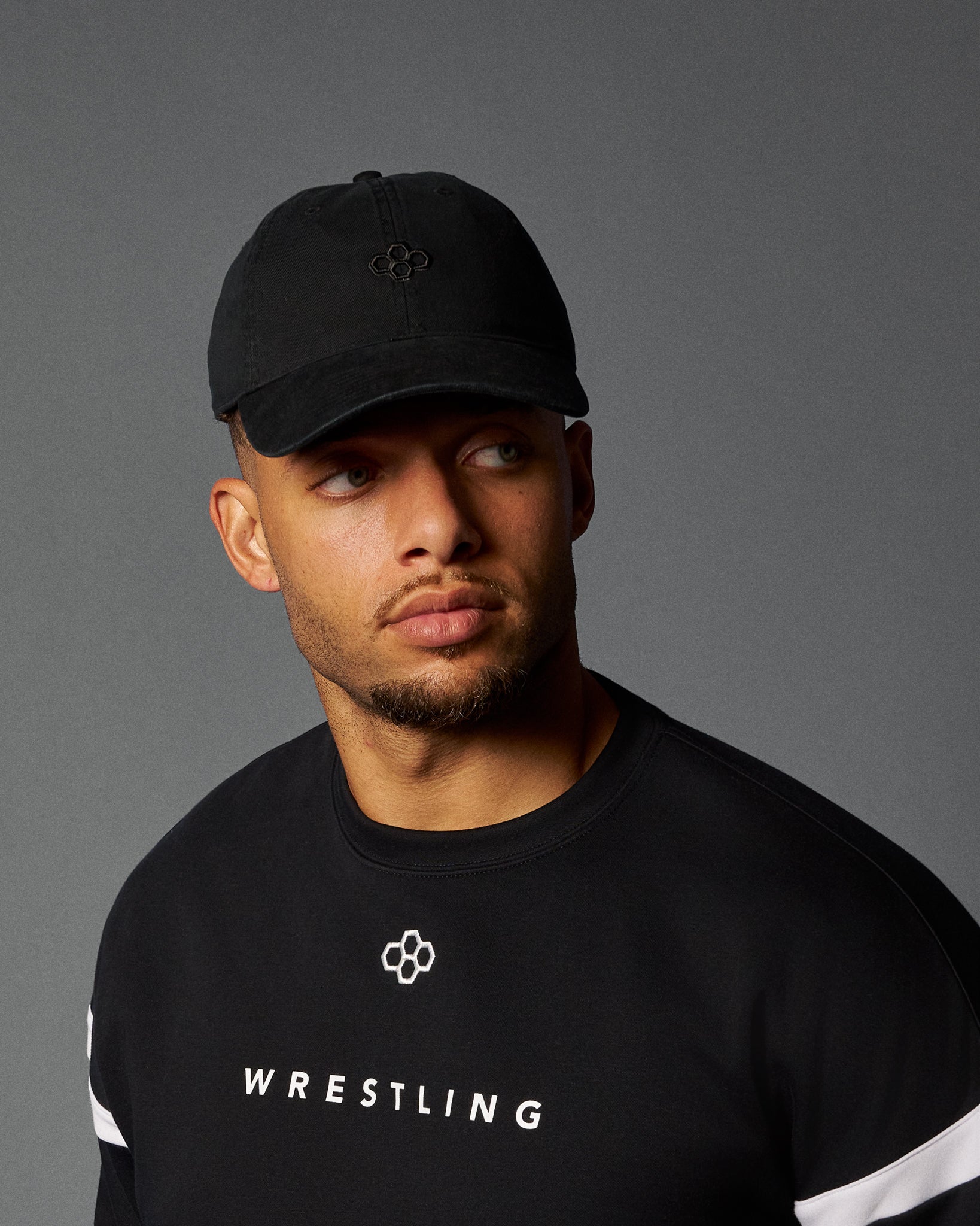 Man wearing a black cap and 'Wrestling' shirt on a gray background
