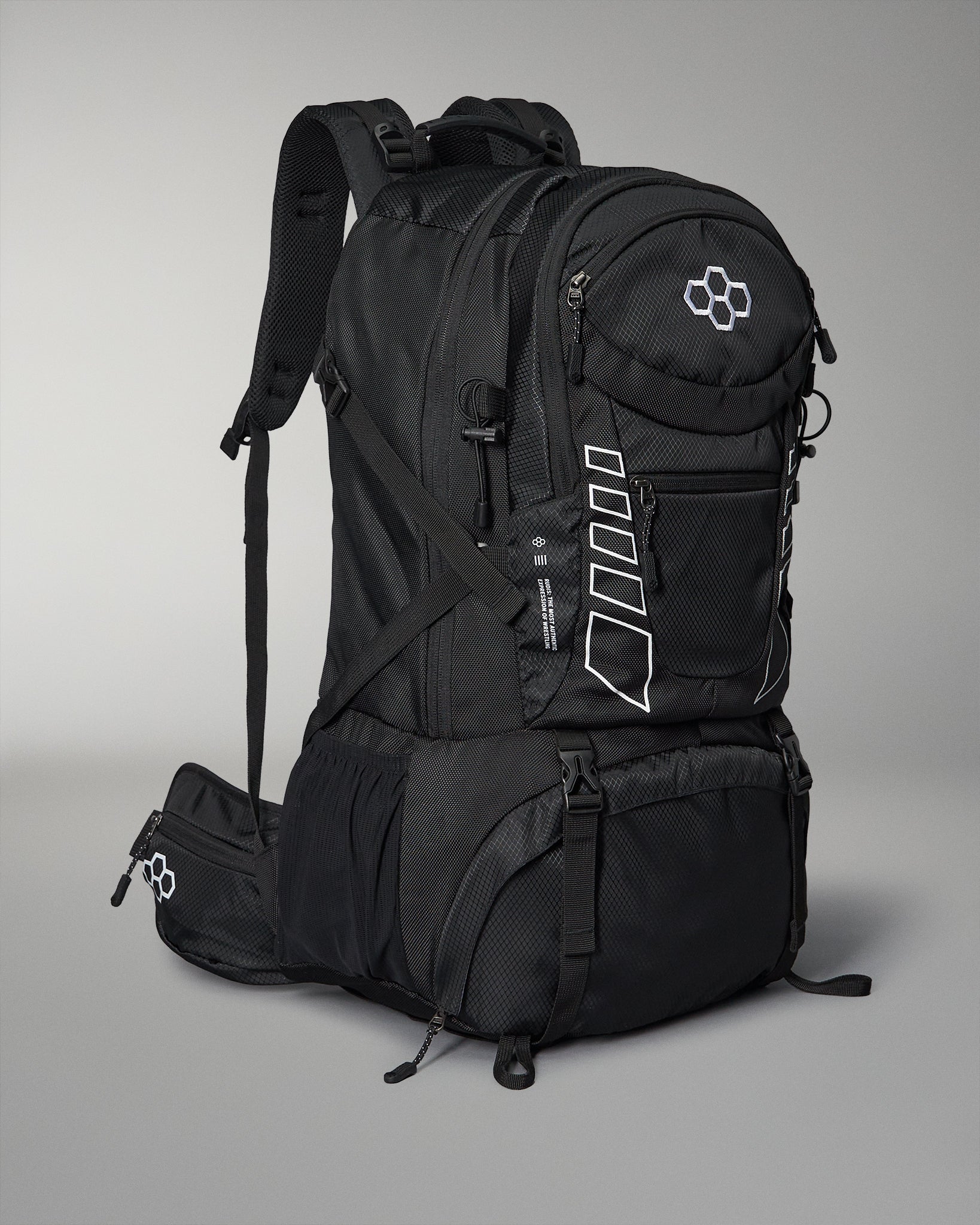 A sleek black wrestling backpack with multiple compartments and adjustable padded straps features white accents and a logo, set against a gray background.