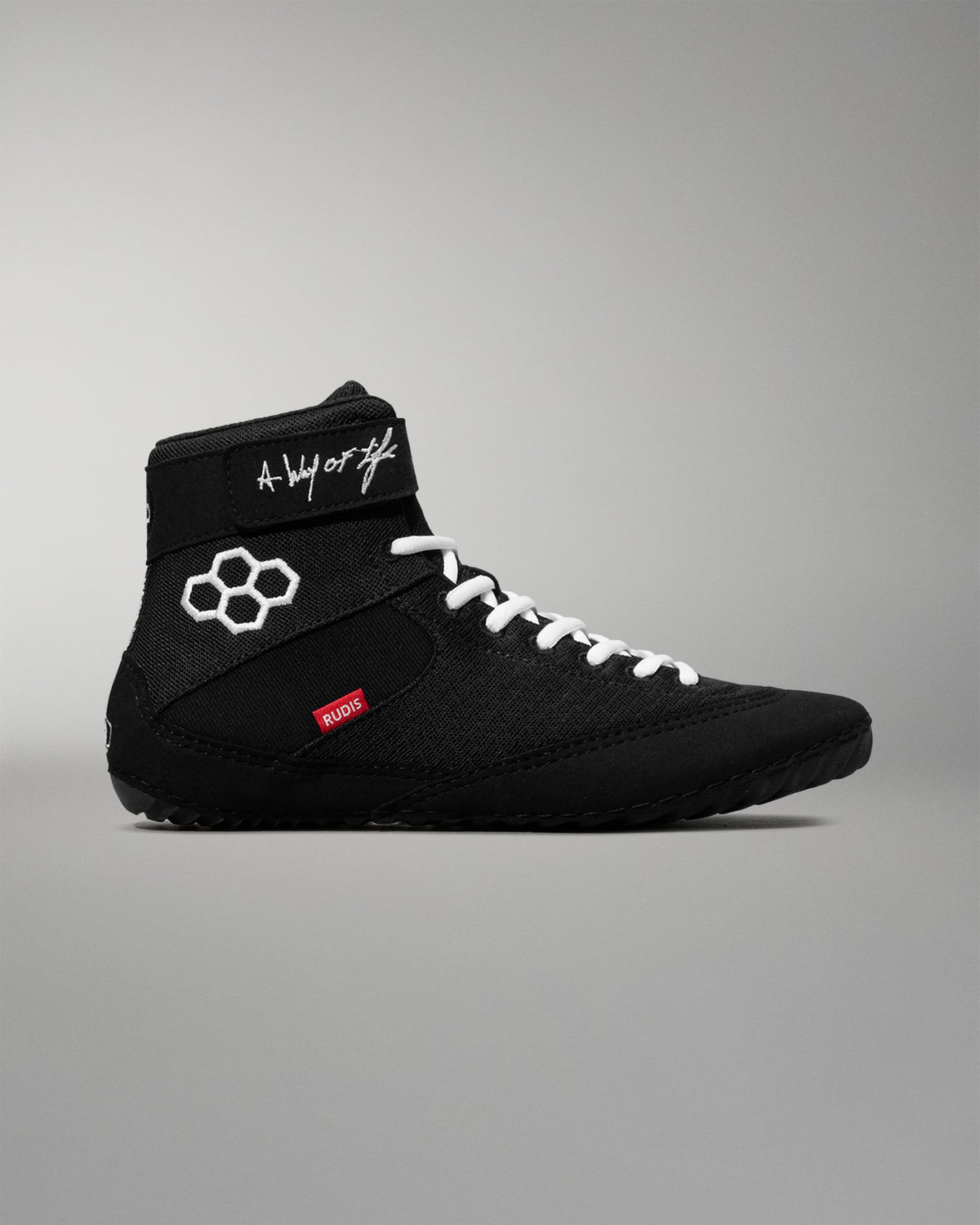 Black wrestling shoe with white laces on a gray background