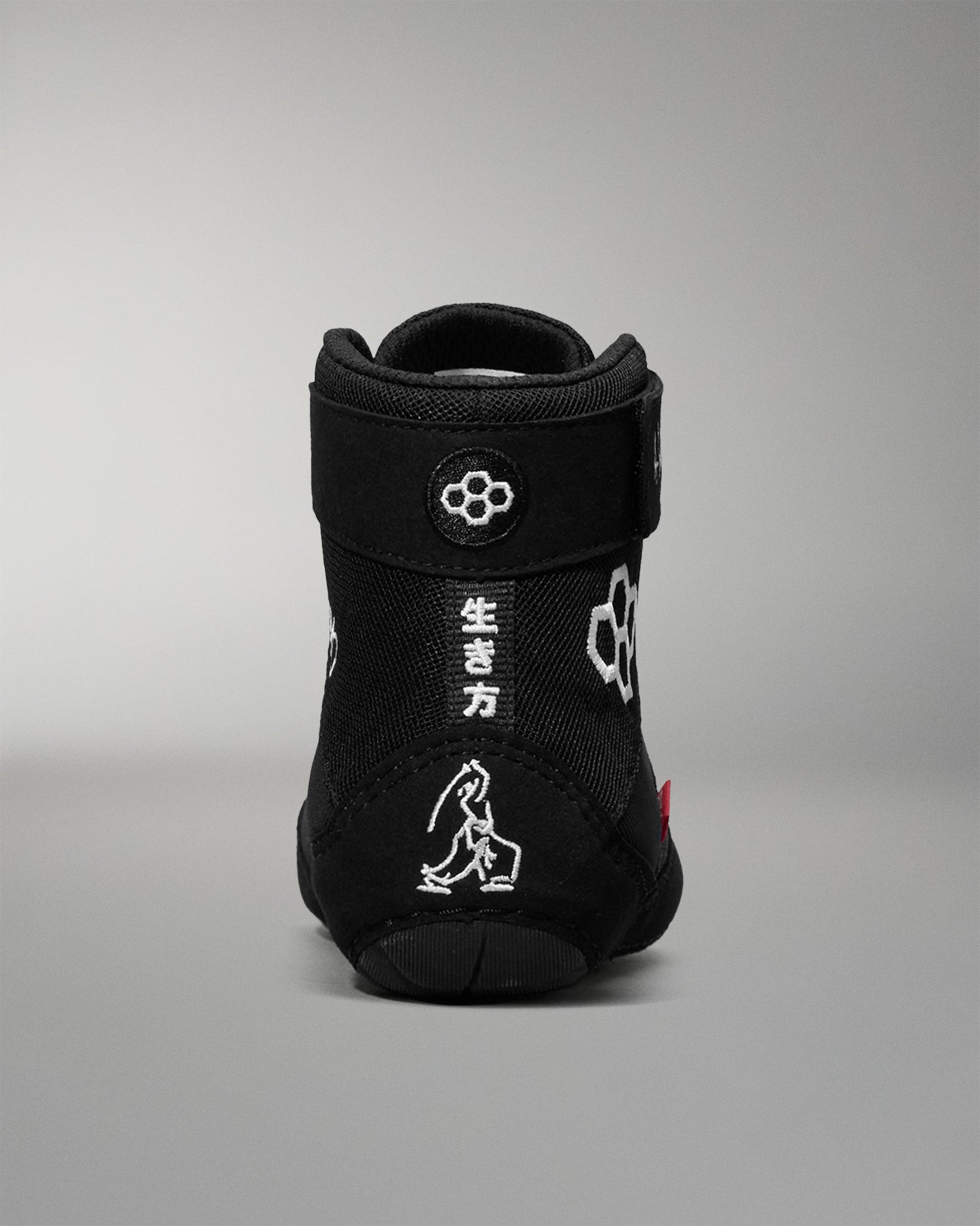 Black wrestling shoe with white designs on a gray background