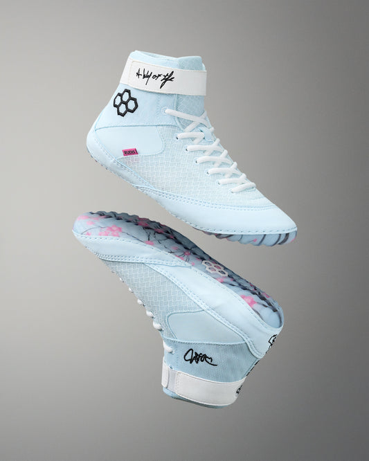 Light blue wrestling shoes with white laces on a gray background