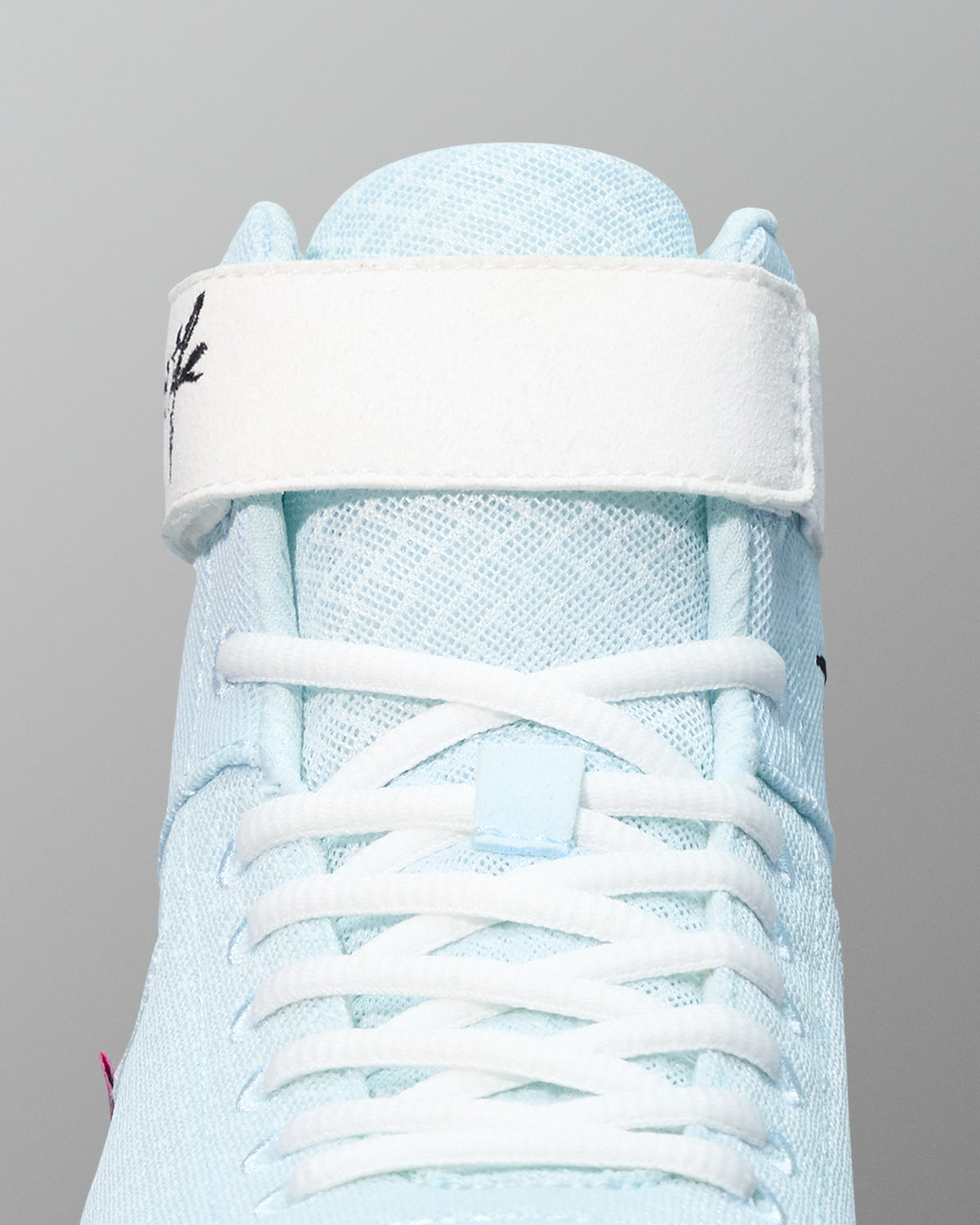 Light blue wrestling shoe with white laces on a gray background