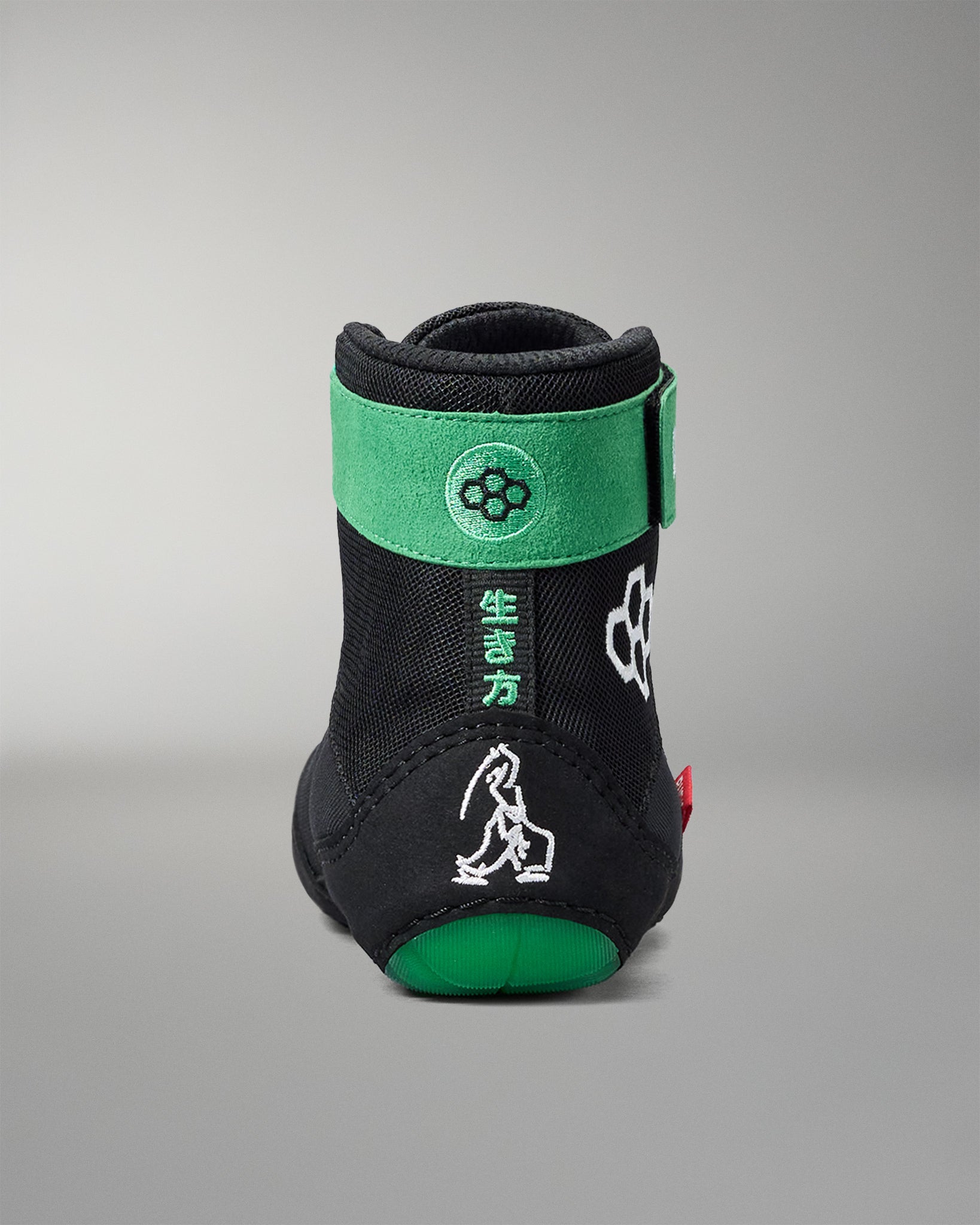 Black and green wrestling shoe with brand logo on a gray background