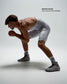 Wrestler, Marcus Blaze, wearing RUDIS Samurai Speed Adult Wrestling Shoes in Kokoro with a white wrestling singlet, demonstrating the high-top design in a low wrestling stance.